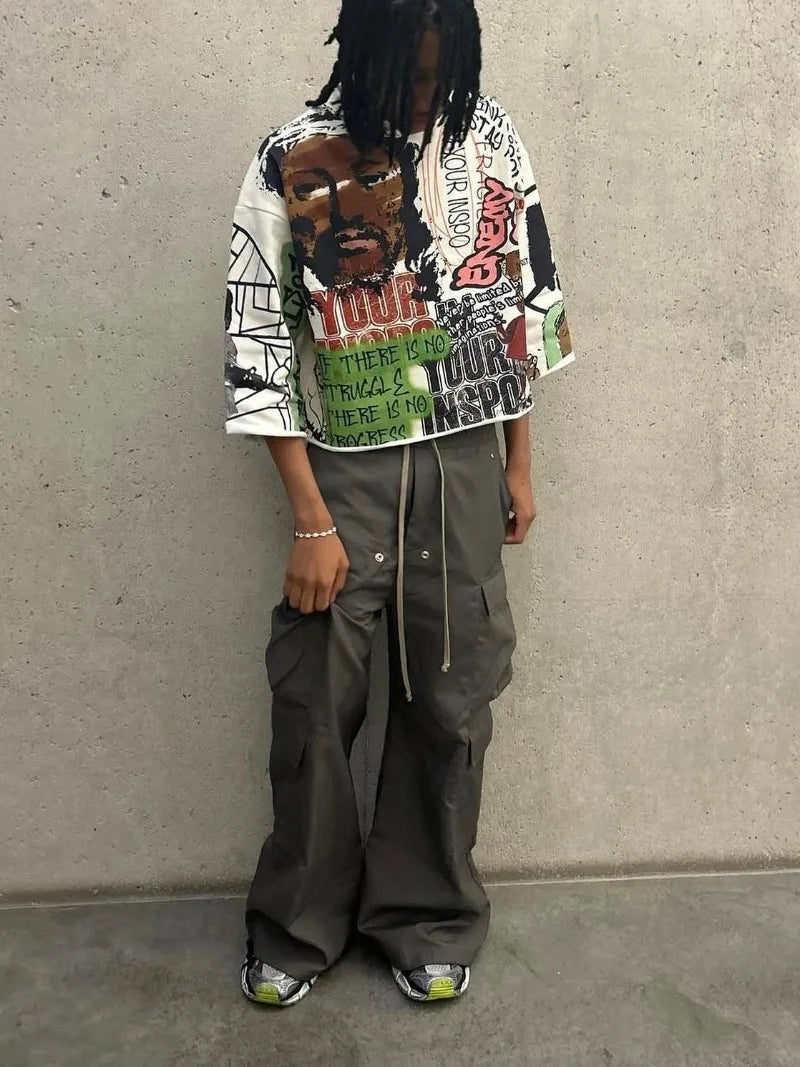 Person wearing a colorful graphic hoodie and gray pants against a plain background